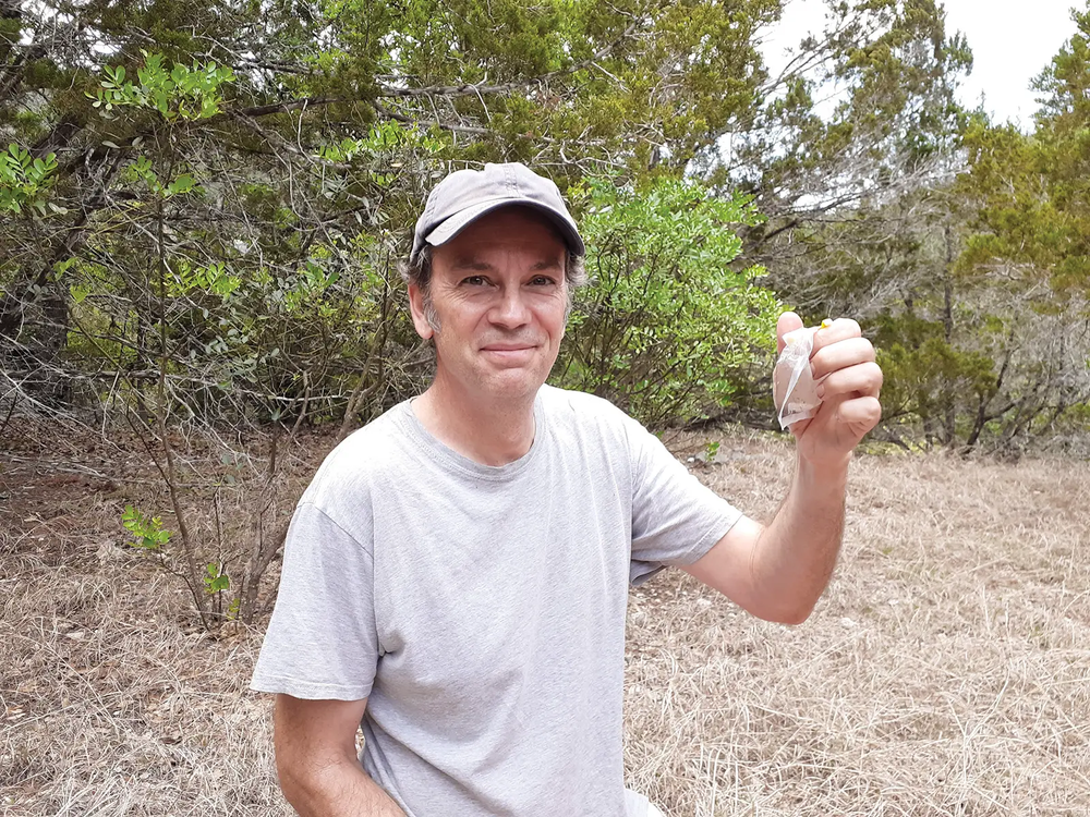 person in a cap holding a liquid filled bag