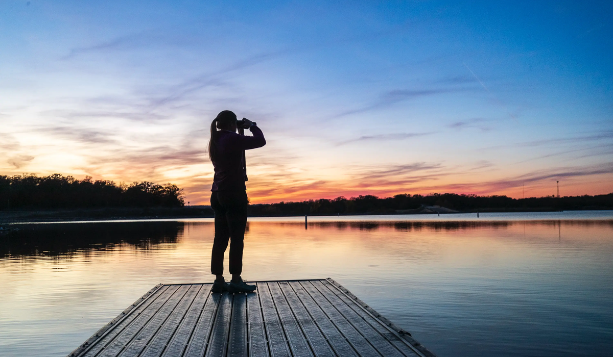 person standing on a floating platform using binoculars