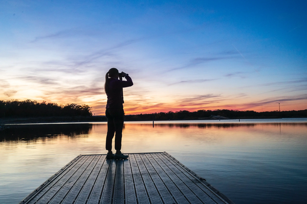 person standing on a floating platform using binoculars