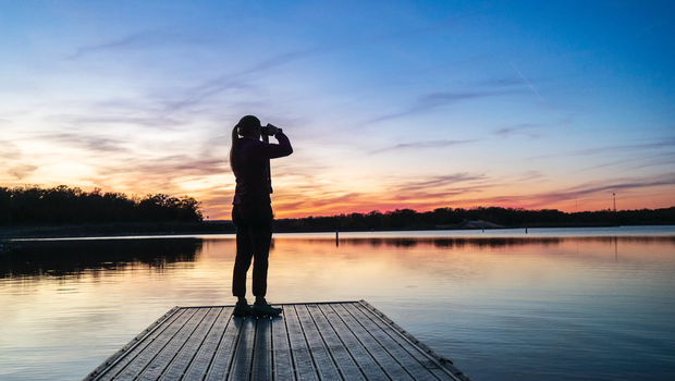person standing on a floating platform using binoculars