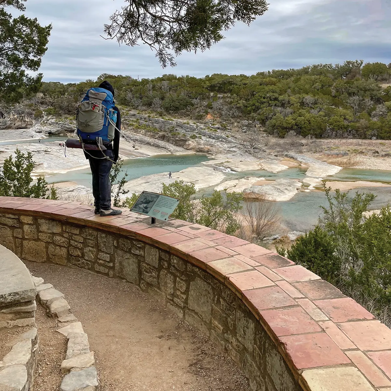 person standing on a rock wall overlooking Pedernales Falls