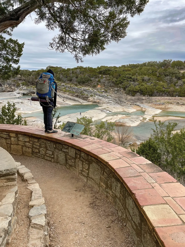 person standing on a rock wall overlooking Pedernales Falls