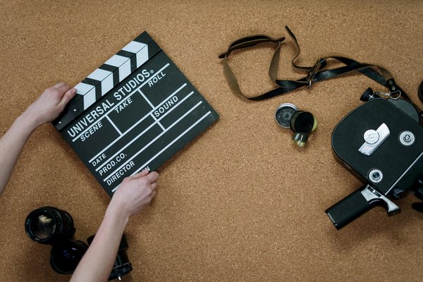 Person holding a black and white clapperboard with a camera and lenses