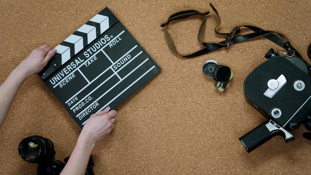 Person holding a black and white clapperboard with a camera and lenses