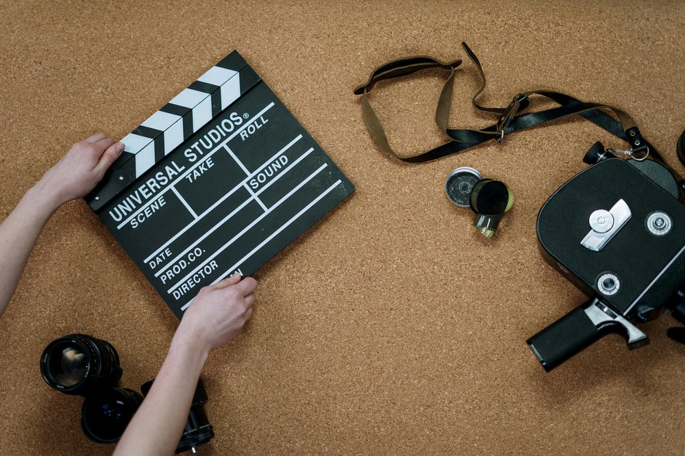 Person holding a black and white clapperboard with a camera and lenses