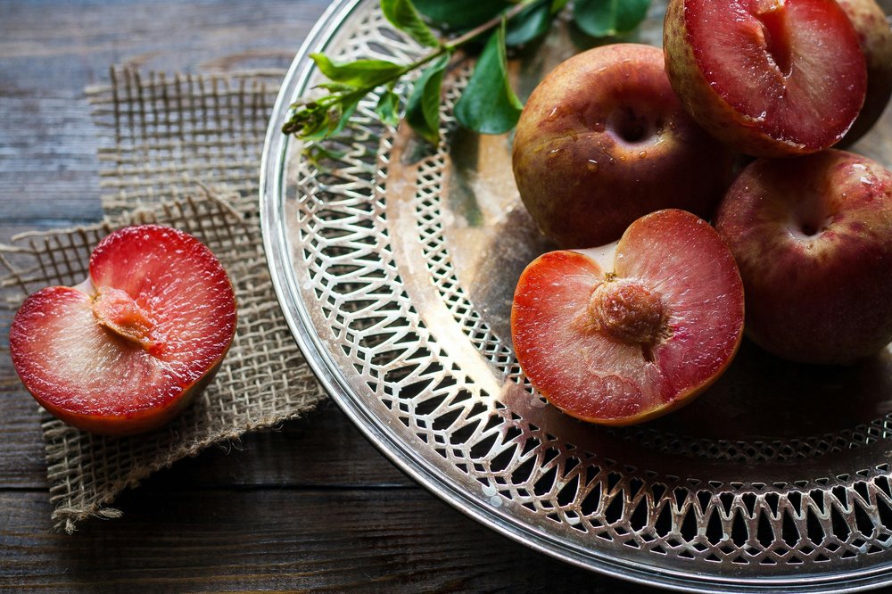 platter of plums some sliced in half