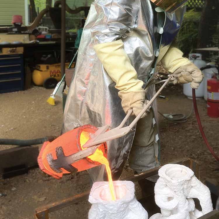 A man pours molten material into a cast