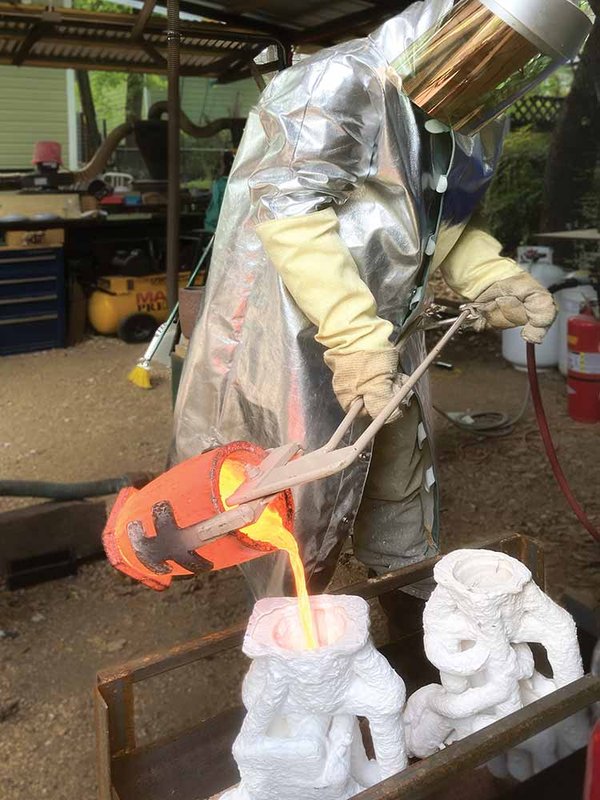 A man pours molten material into a cast