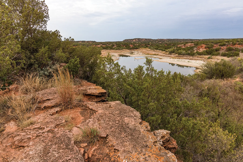 rocky cliff overlooking a pond in a texas state park