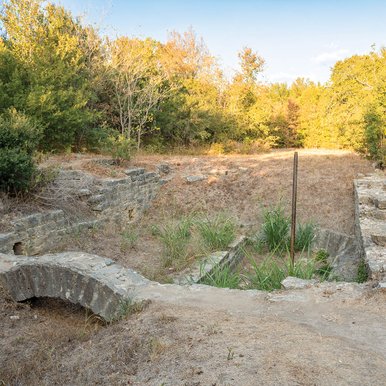 Ruins of a gristmill structure surrounded by trees.