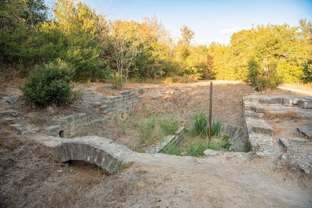 Ruins of a gristmill structure surrounded by trees.