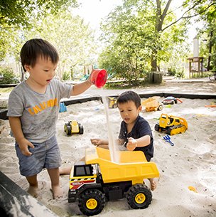 child playing with a sand truck in a natural playscape