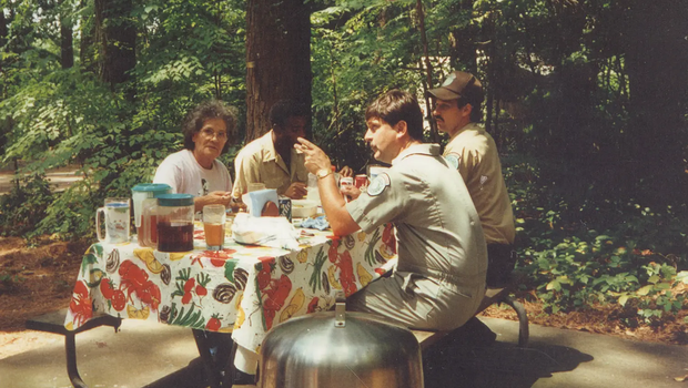 texas parks and wildlife staff picnic at a picnic table in the woods.