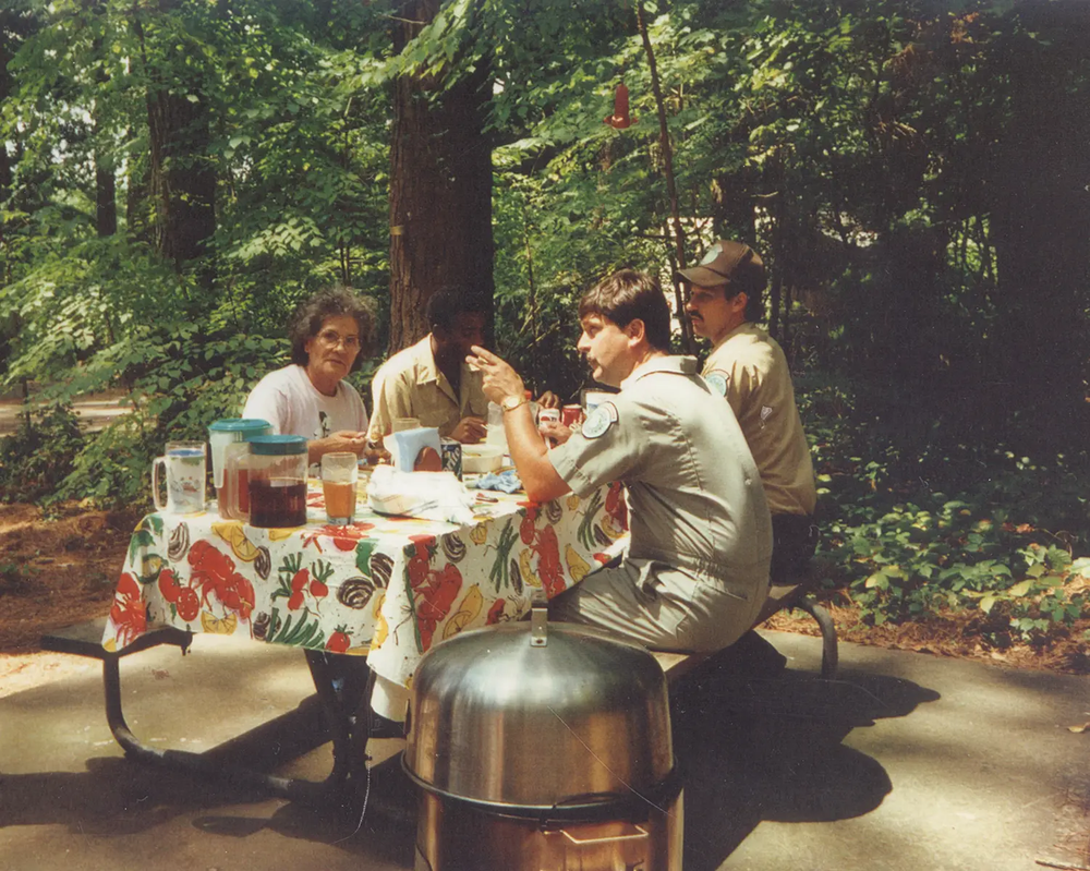 texas parks and wildlife staff picnic at a picnic table in the woods.