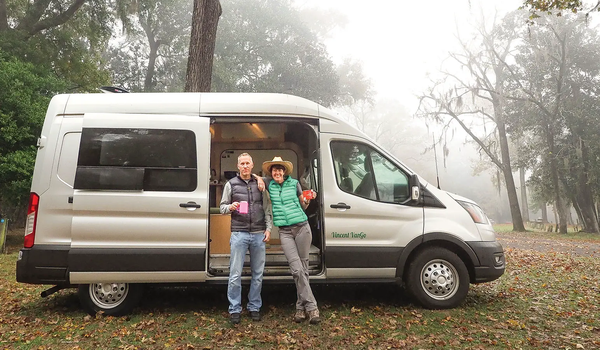 two people outside of their camper van