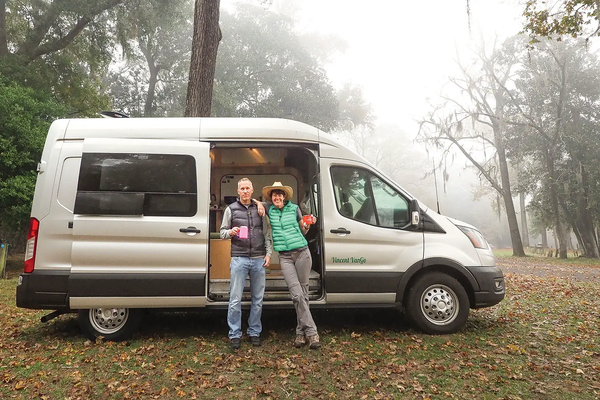 two people outside of their camper van