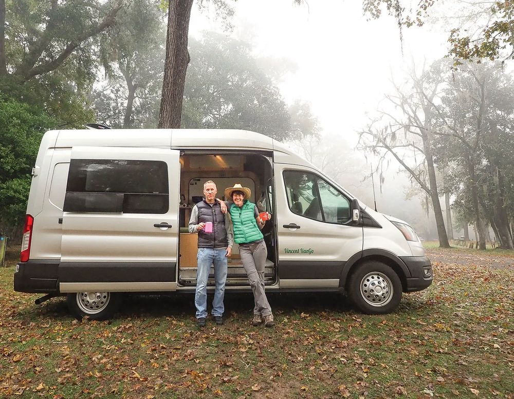 two people outside of their camper van