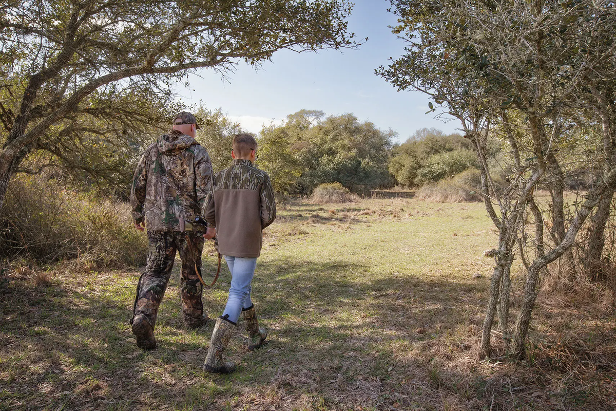 two people walking out of a wooded area into a clearing