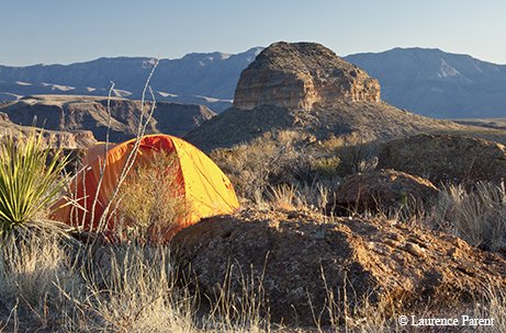 tent pitched on rocky terrain overlooking  the tops of canyons.