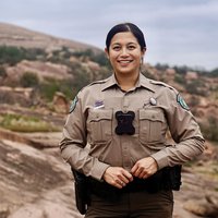 A game warden in uniform in a rocky outdoor area