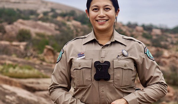 A game warden in uniform in a rocky outdoor area