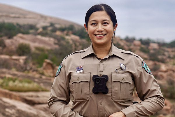 A game warden in uniform in a rocky outdoor area