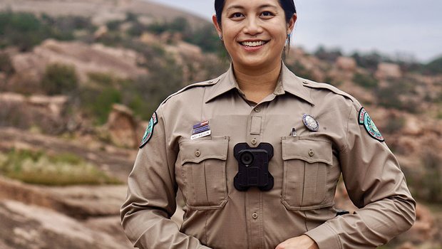 A game warden in uniform in a rocky outdoor area