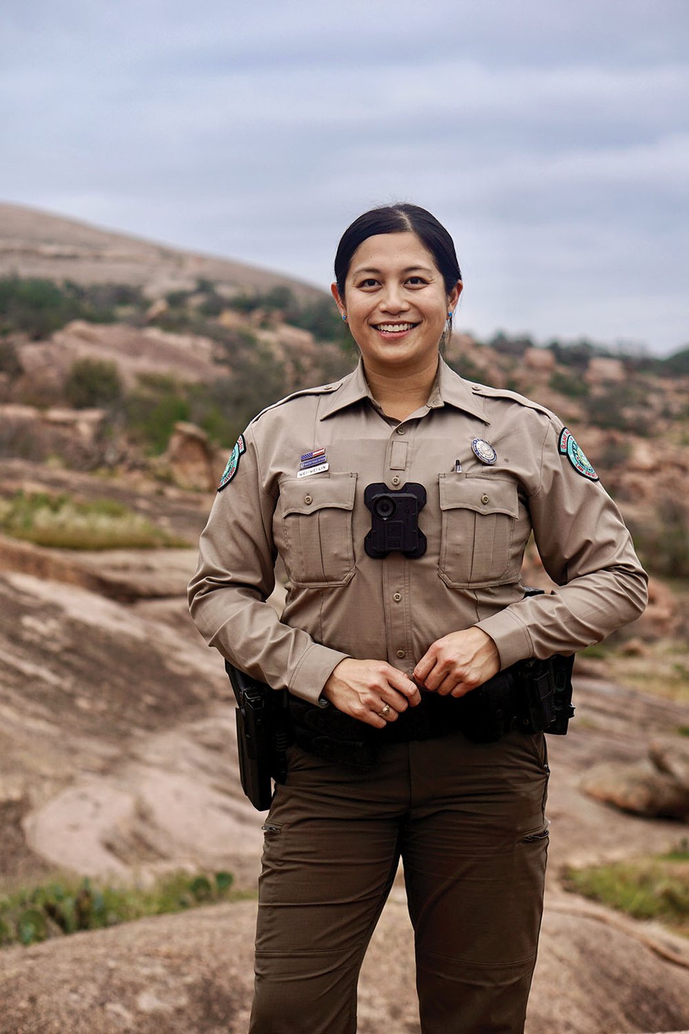 A game warden in uniform in a rocky outdoor area
