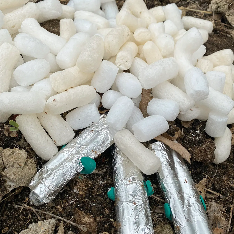 white pellets with tubes covered in foil being held by green clamps