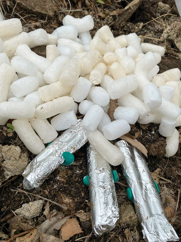 white pellets with tubes covered in foil being held by green clamps