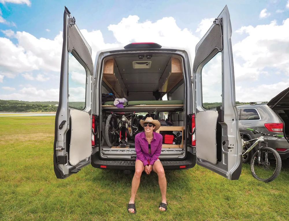 woman sitting on the back of her camper van